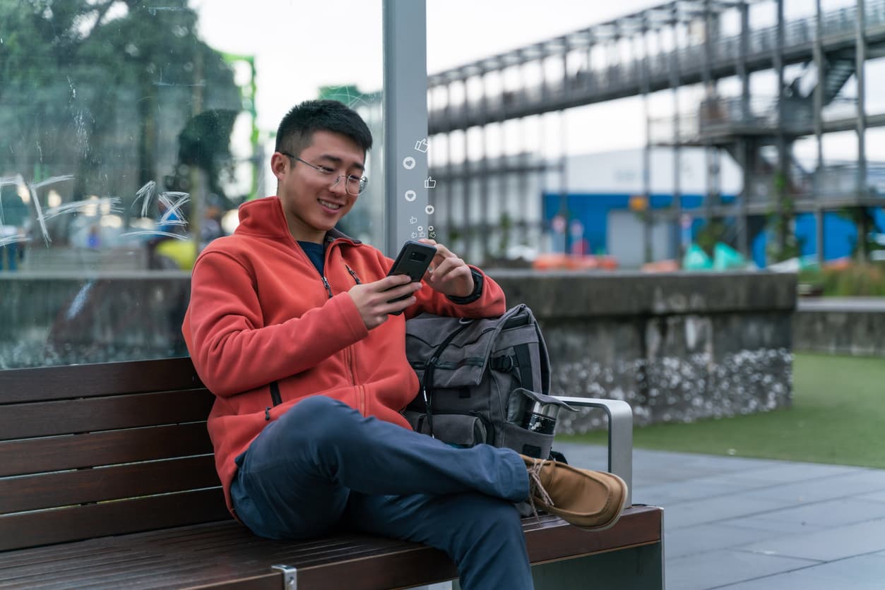 Young man using his phone to bank online in Auckland, new Zealand